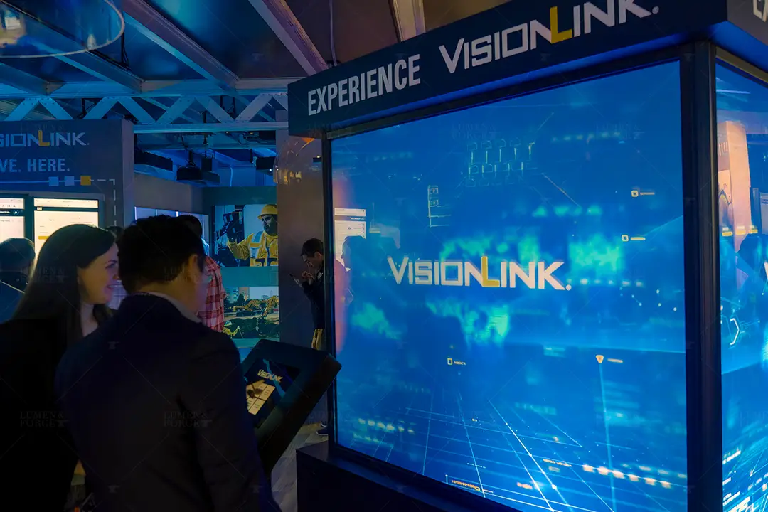 Attendees beside the Experience VisionLink projection-mapped cube and touchscreen kiosk at the Caterpillar Con Expo booth