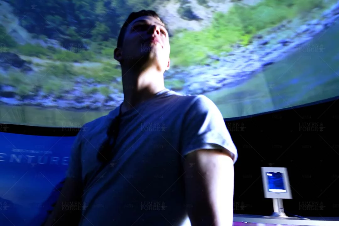 Visitor gazing up at a mountain landscape projected inside the Capital One Venture Dome in Denver