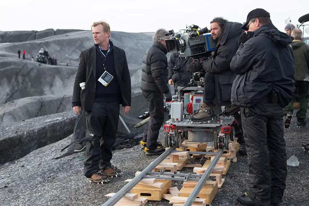 Behind the scenes on the Interstellar film set, crew with an IMAX camera on a dolly track in a rocky landscape