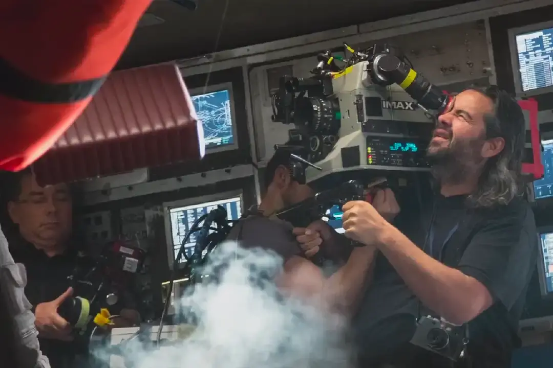 Camera operator filming Interstellar with an IMAX camera on a cockpit set lined with monitors and smoke