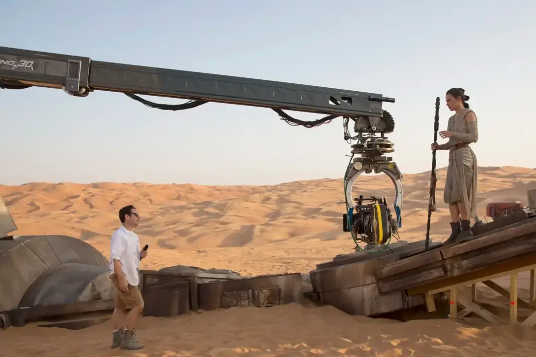 Star Wars: The Force Awakens desert film set with a camera crane aimed at an actor holding a staff on a platform