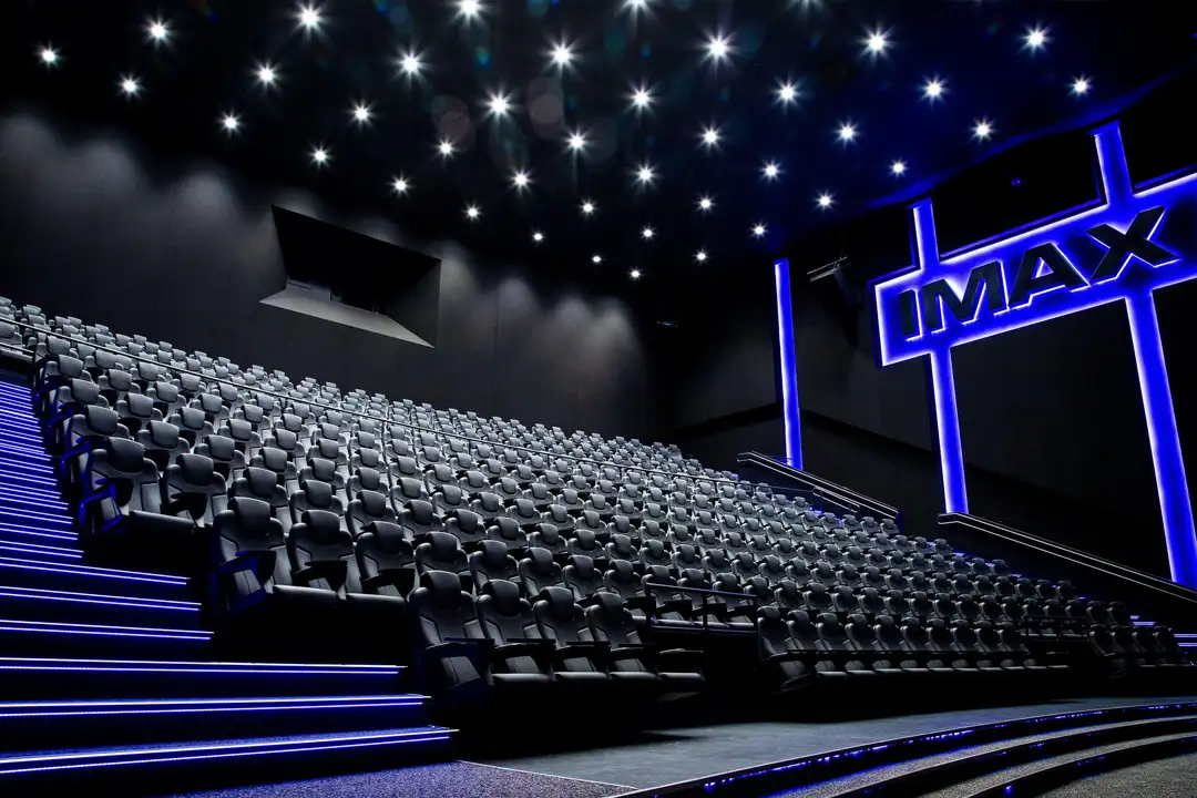IMAX theater in Helsinki, Finland with tiered black recliner seats, a starry ceiling and a blue-lit IMAX sign