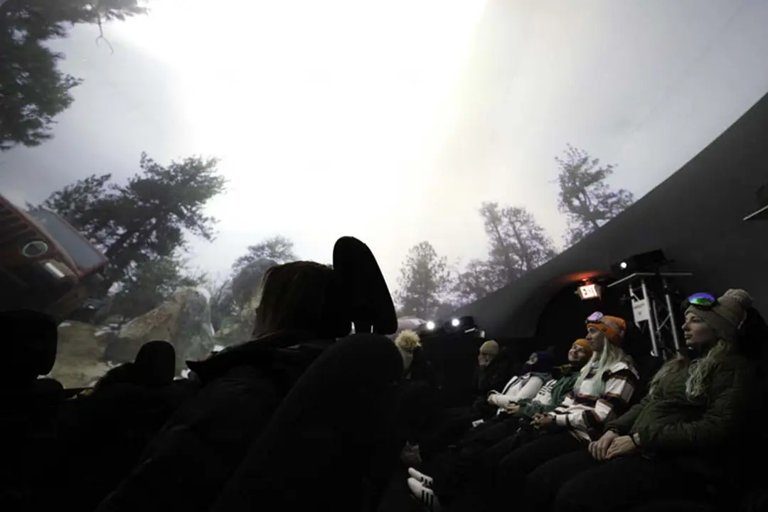 Audience in reclined seats inside the Jeep 4D experience dome, watching a projected forest and off-road scene