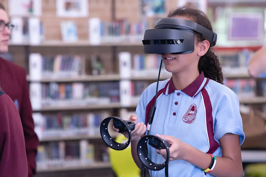 Student in a school uniform wearing a VR headset and holding motion controllers in a library, VR in education