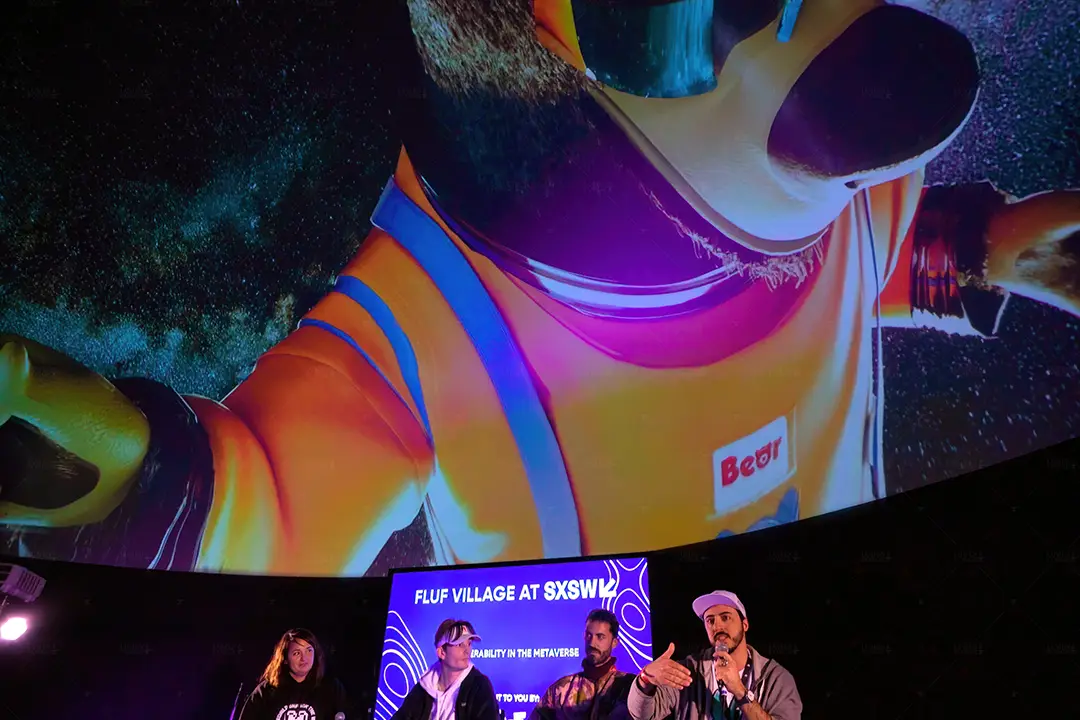 Panelists on stage beneath a giant projected astronaut character in the Fluf Village dome at SXSW