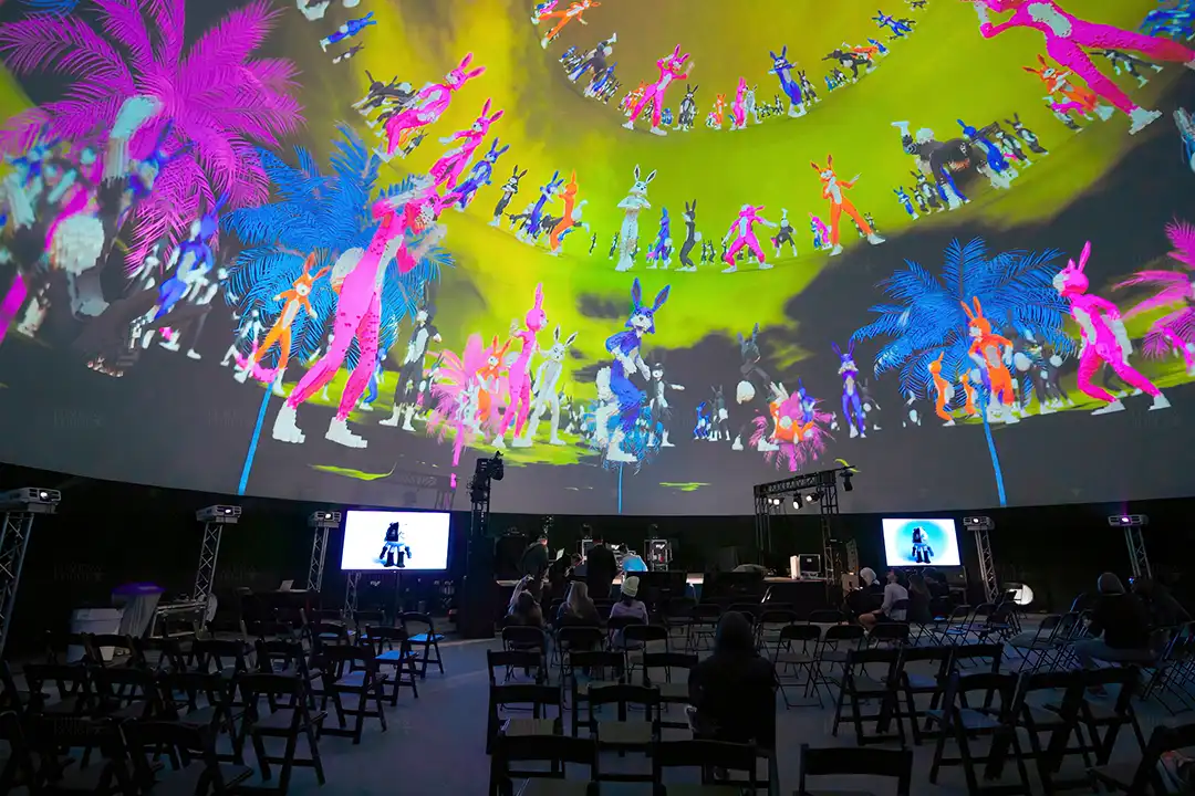 Colorful rabbit characters and palm trees projected across a dome at South by Southwest in Austin, above rows of chairs