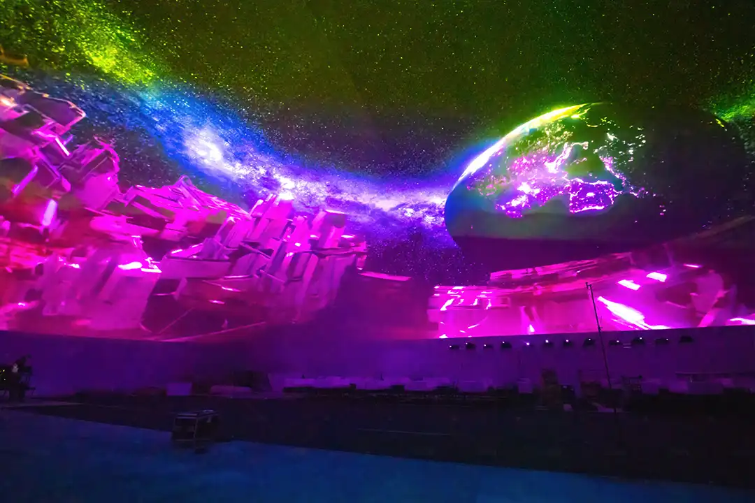 Interior of Miami's largest projection dome featuring a crowd under immersive neon sky visuals.