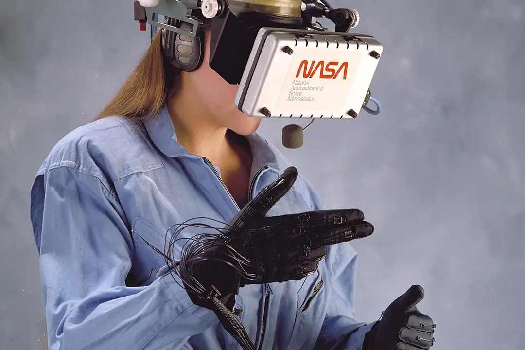 Woman wearing a NASA-labeled head-mounted display and a wired data glove, part of NASA's Virtual Visual Environment Display