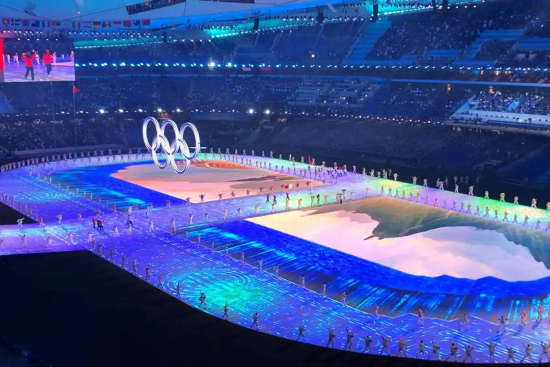 Projection-mapped stadium floor with the Olympic rings at the Beijing 2022 Winter Olympics opening ceremony