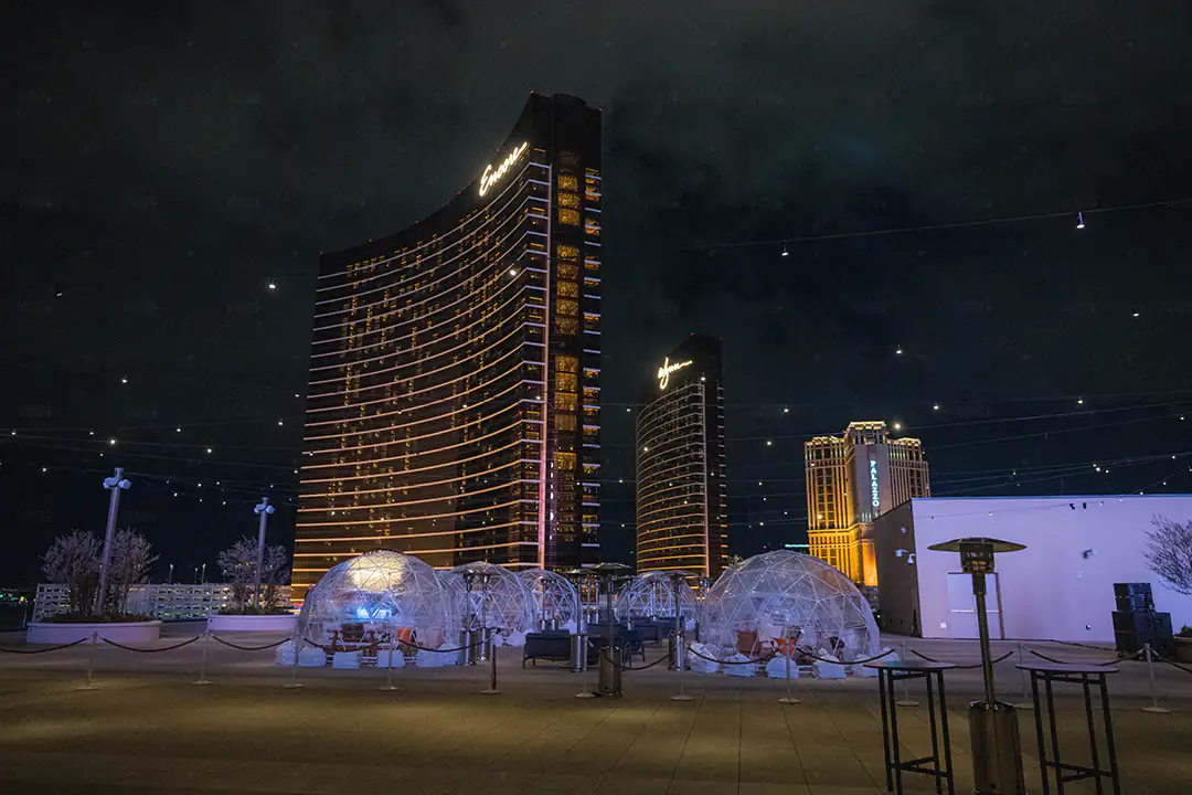 Illuminated igloo domes on the Resorts World rooftop at night, with glowing Las Vegas Strip hotel towers behind