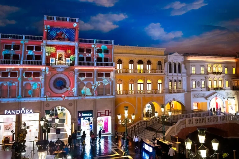 Clock tower at St. Mark's Square lit with red and teal holiday projections above Pandora and other shops, Venetian Las Vegas