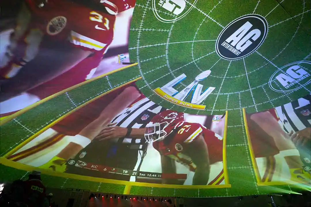Super Bowl LV game footage projected across the curved ceiling of The Dome, with AG Entertainment logos and a KC player close-up