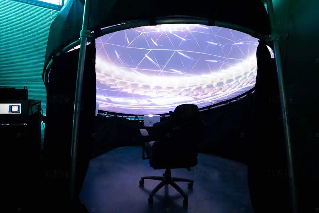 Gaming chair inside a compact home VR dome, with a glowing projected visual across the curved screen overhead