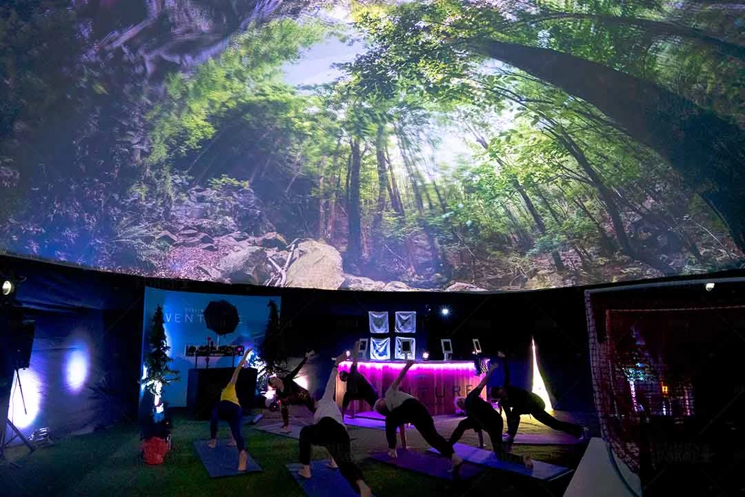 Yoga class inside Capital One's 360 projection dome with a forest canopy projected overhead