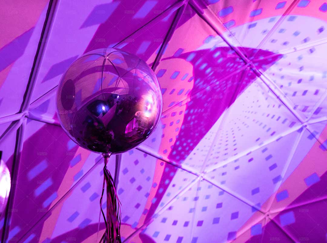 Closeup of metal sphere reflecting geometric content projected on interior of dome