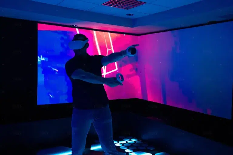 man playing virtual reality game beat saber with video display behind him