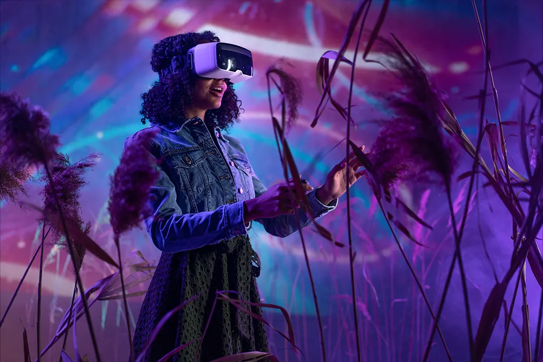 Woman with virtual reality goggles experiencing a virtual world of purple vibrant colors