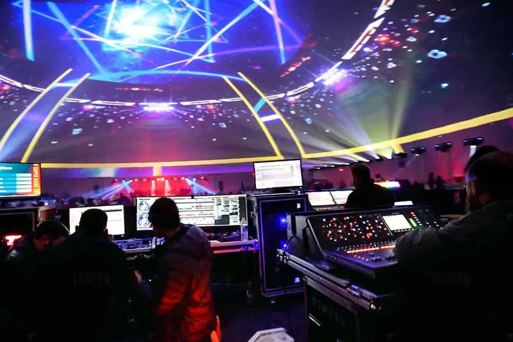 Live event projection mapping inside a dome, with audiovisual engineers managing real-time immersive visuals and lighting control.