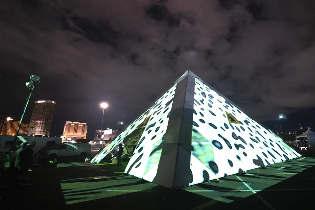 Projection mapping on a pyramid-shaped structure at Area 15 during a New Year's Eve event in Las Vegas with the city skyline in the background.