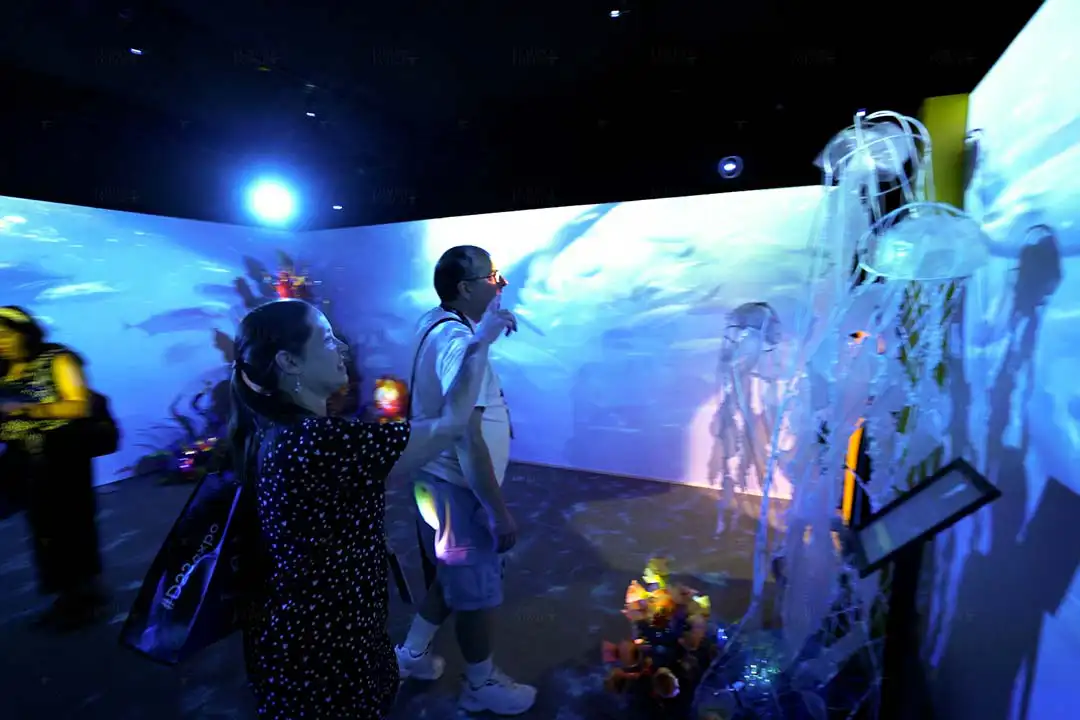 Guests interacting with immersive underwater visuals using 360-degree projection mapping technology at a Nat Geo exhibit.